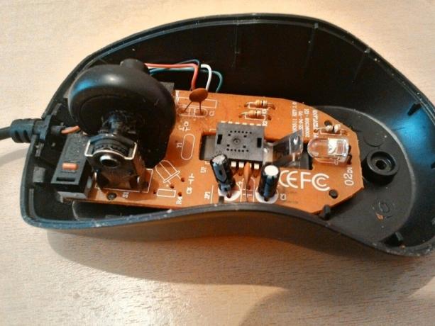 Și uite spre interior, dacă ați scos capacul superior al corpului mouse-ului. Deci, optica aproape nu sunt vizibile. Pentru a ajunge la ea, trebuie să ridice taxa, nu este înșurubată. 